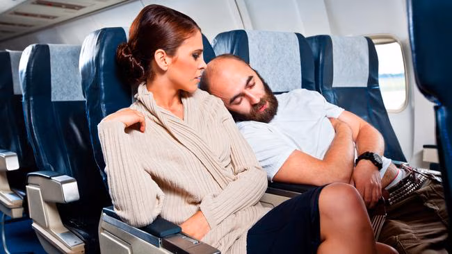 Penumpang tidur nyenyak di kursi pesawat pada red eye flight